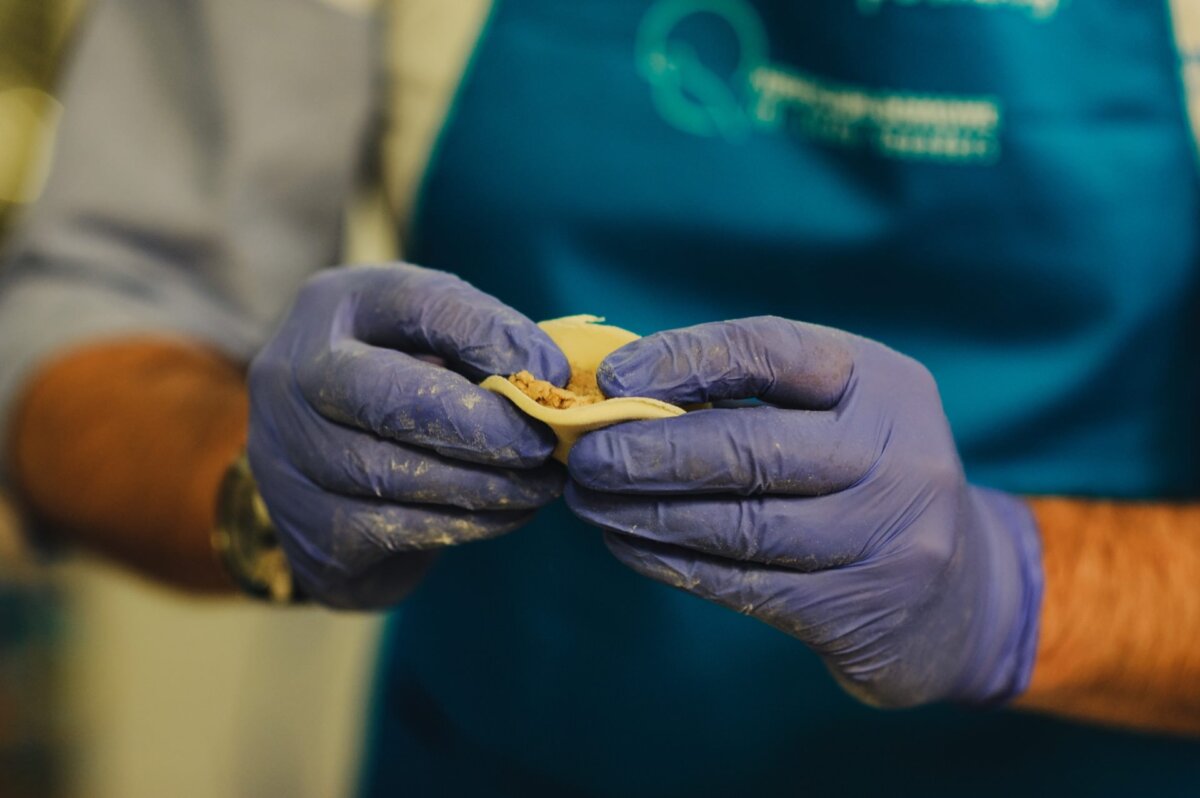 Blue-gloved hands knead the dumpling