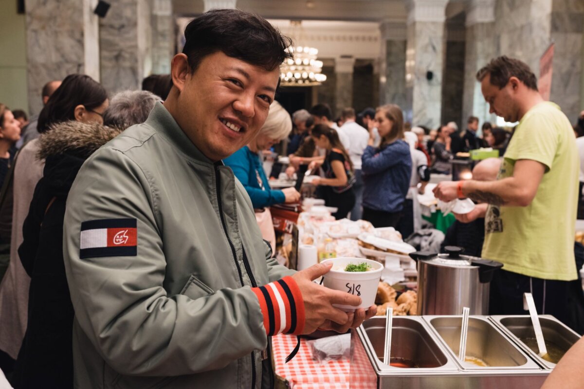 Asian man holding soup in a white bowl