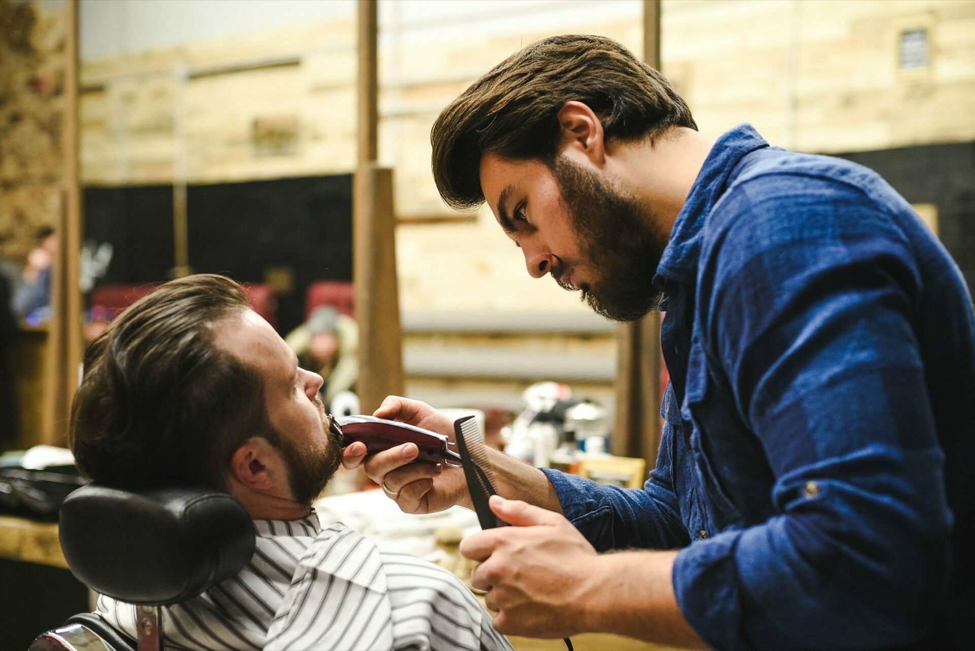 Man in blue shirt in barbershop trims beard