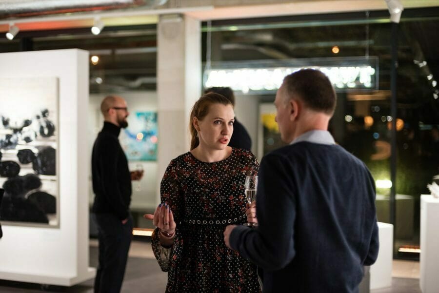 A woman talks while holding a glass of wine and gesturing with her other hand