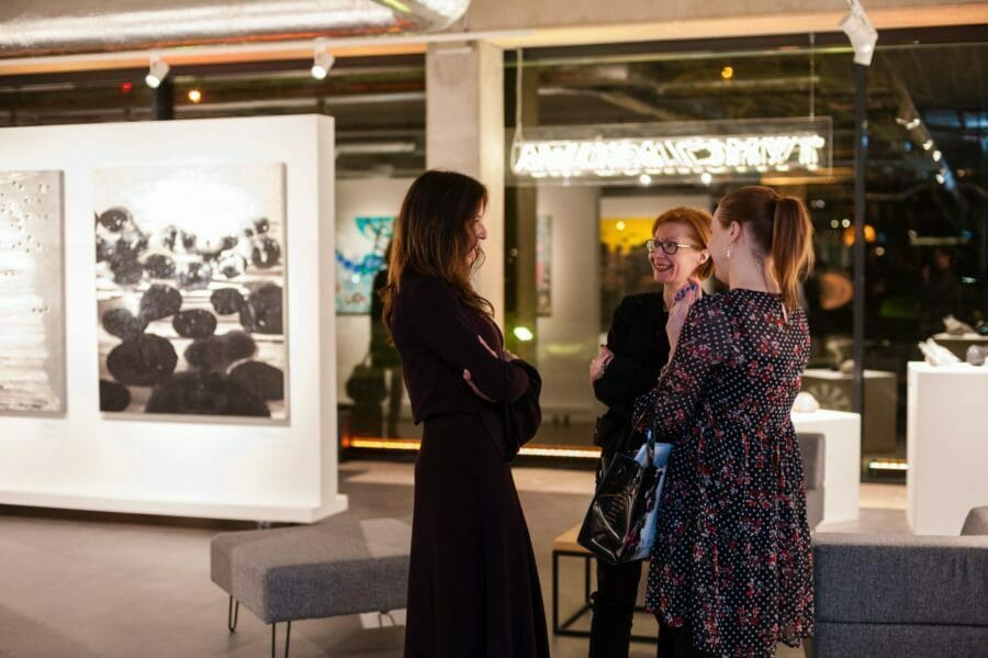 Women talk and laugh at an art gallery in Warsaw, Poland