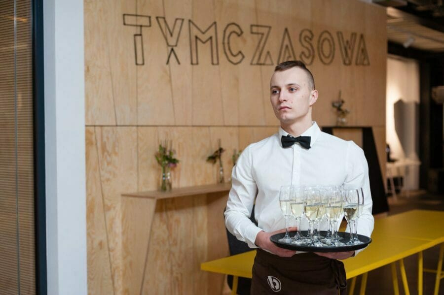 Waiter in champagne glasses at art gallery temporary