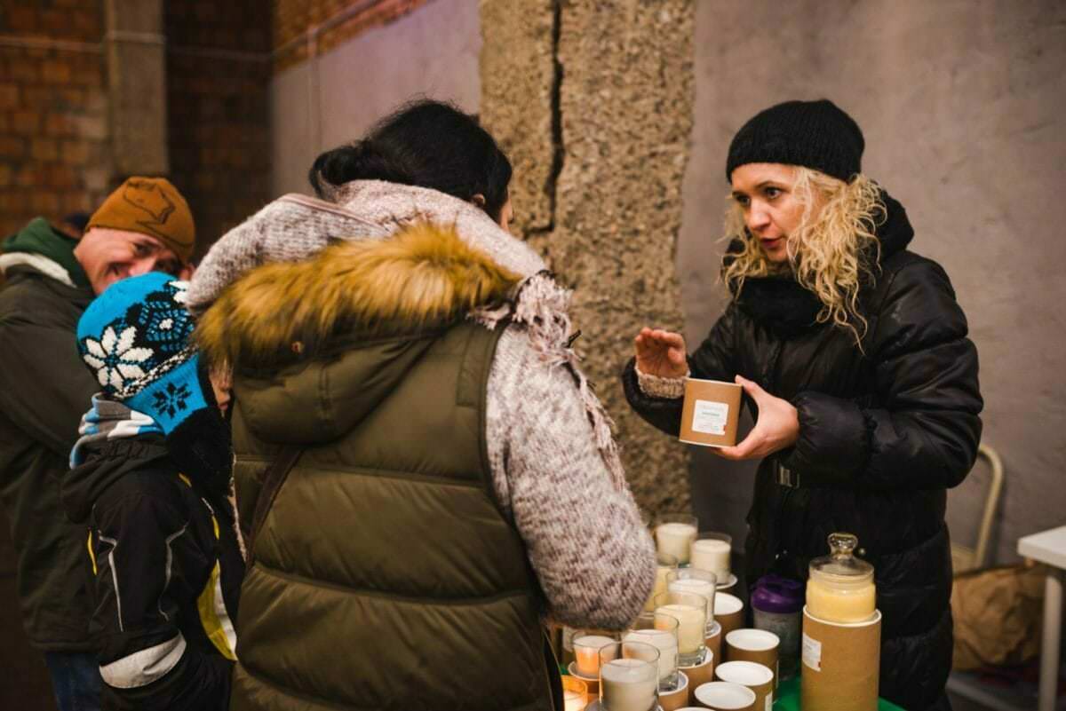 Frau in schwarzer Jacke am natürlichen Kerzenstand