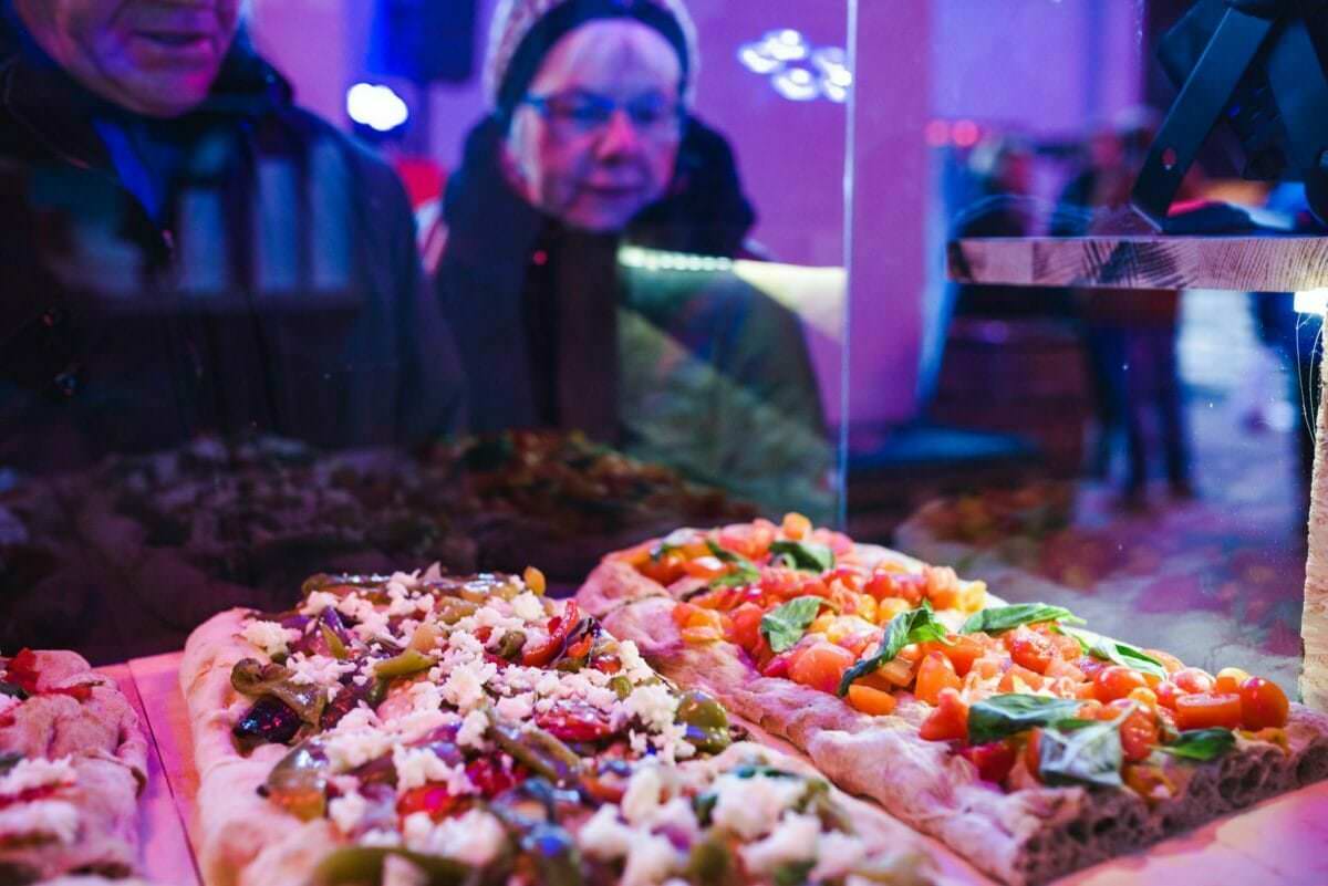 eine Frau schaut durch das Glas auf eine Pizza