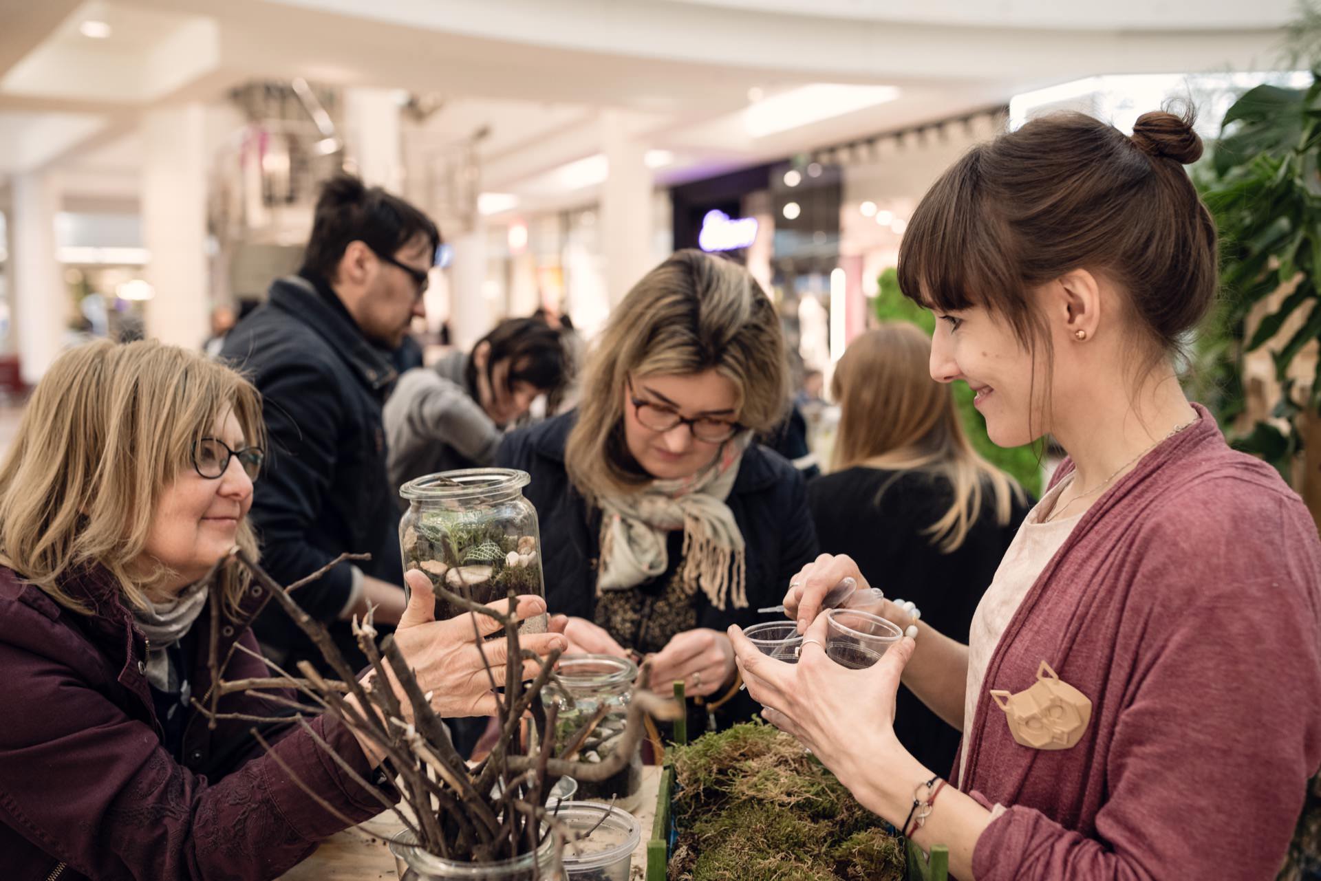 Women arrange forest in jars