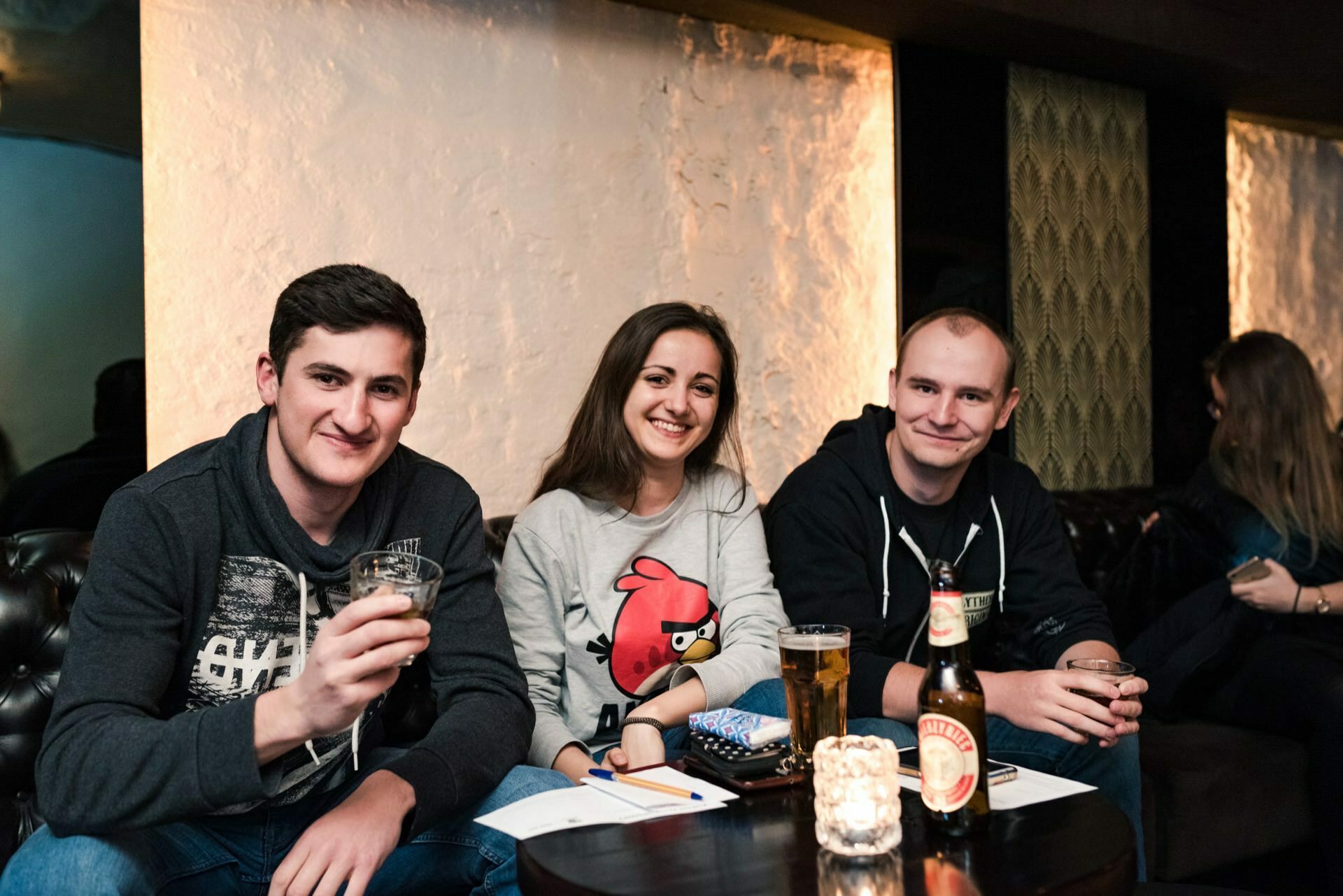 Two men and a woman wearing a gray Angry Birds sweatshirt