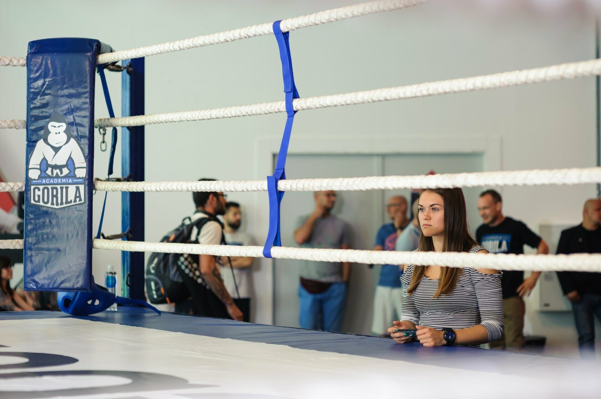 A girl looks through the ropes of the ring