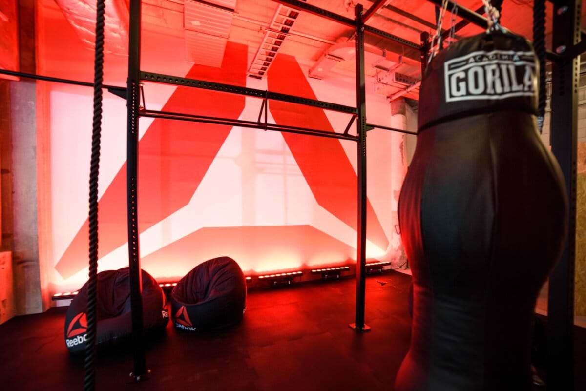 Ściana z logo reebok octagon, worek treningowy i czarne pufy