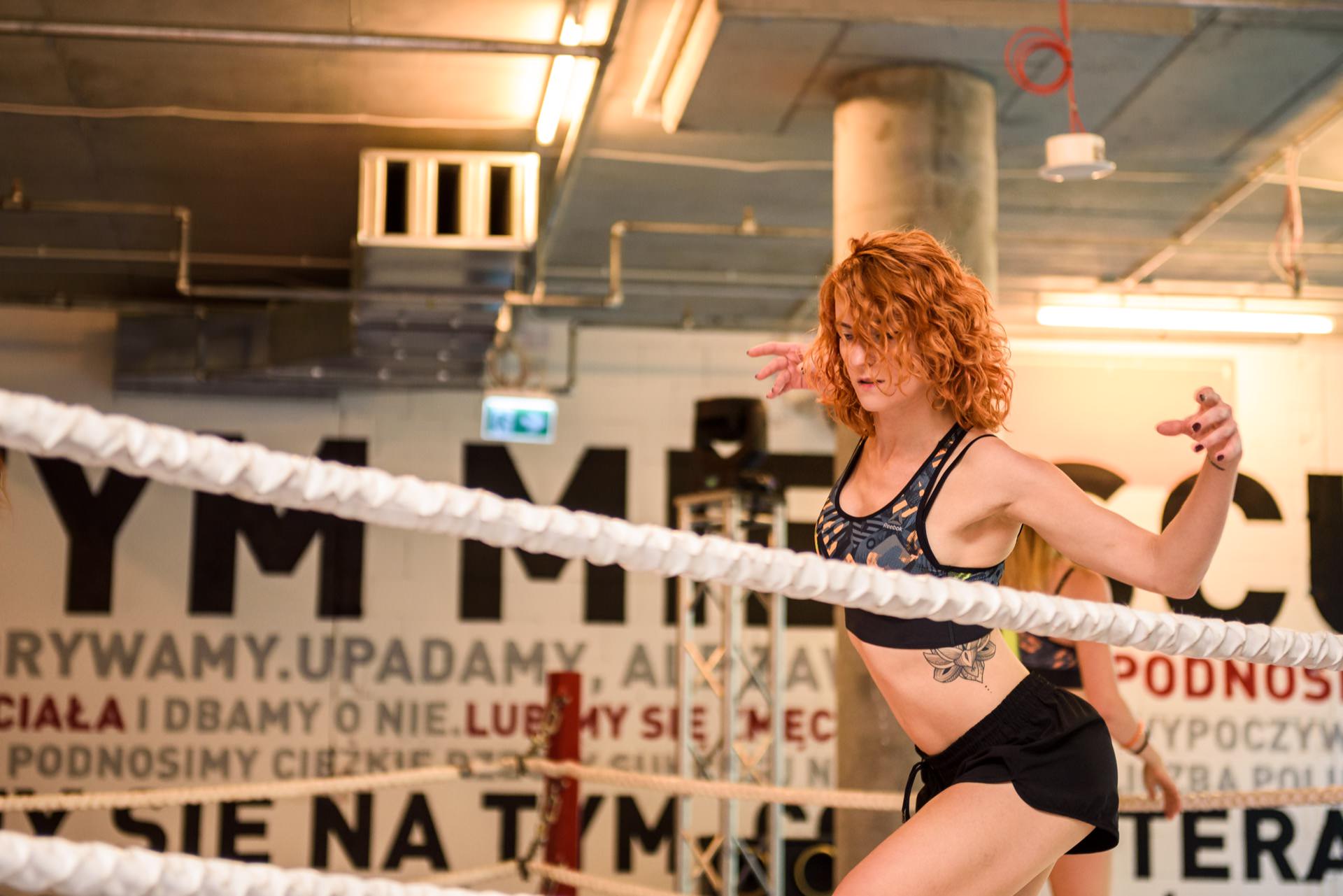 Redheaded girl with tattoo spreads her arms in dance