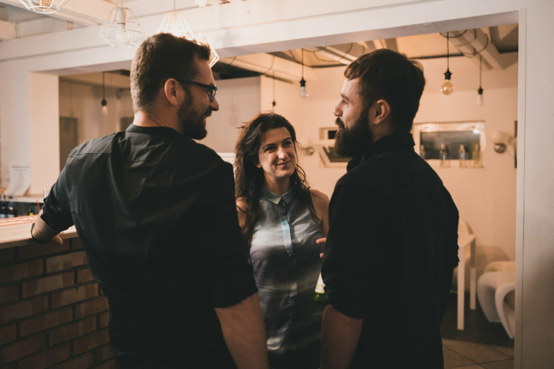 Two men and a woman talk at the bar