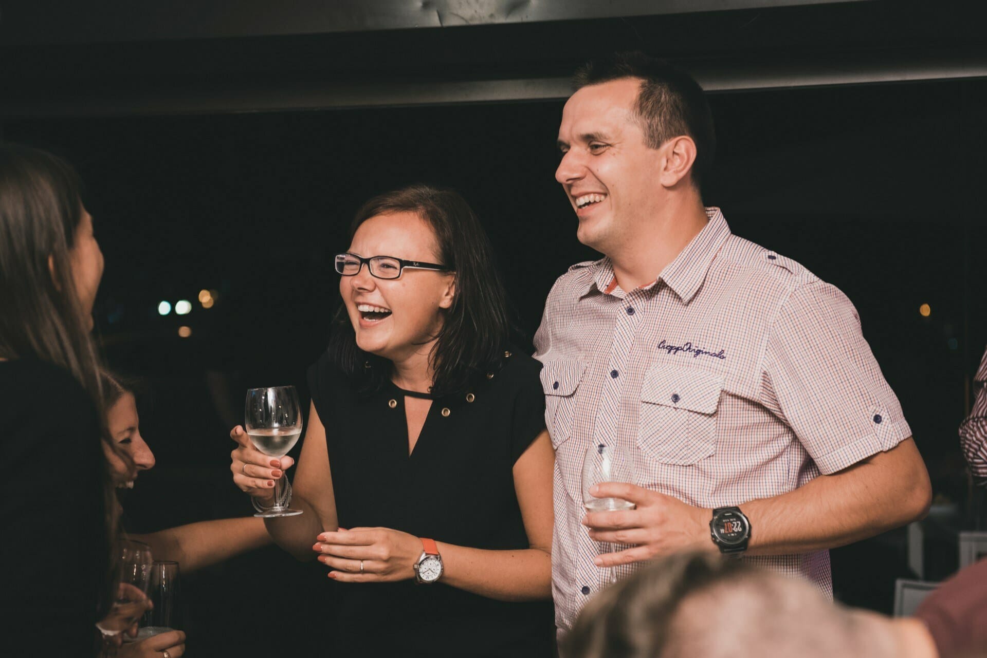 Smiling people at a party with glasses of wine in hand