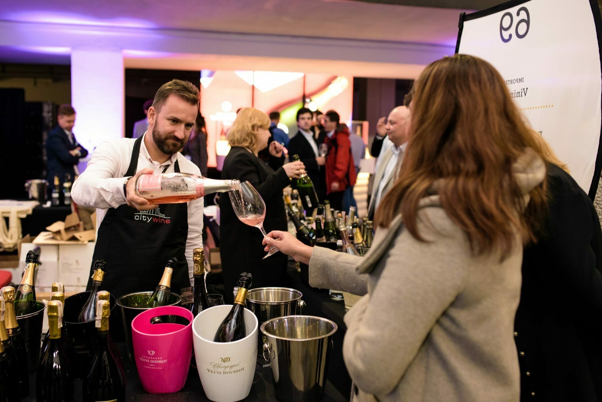 Man with citywine pours pink wine into woman's glass