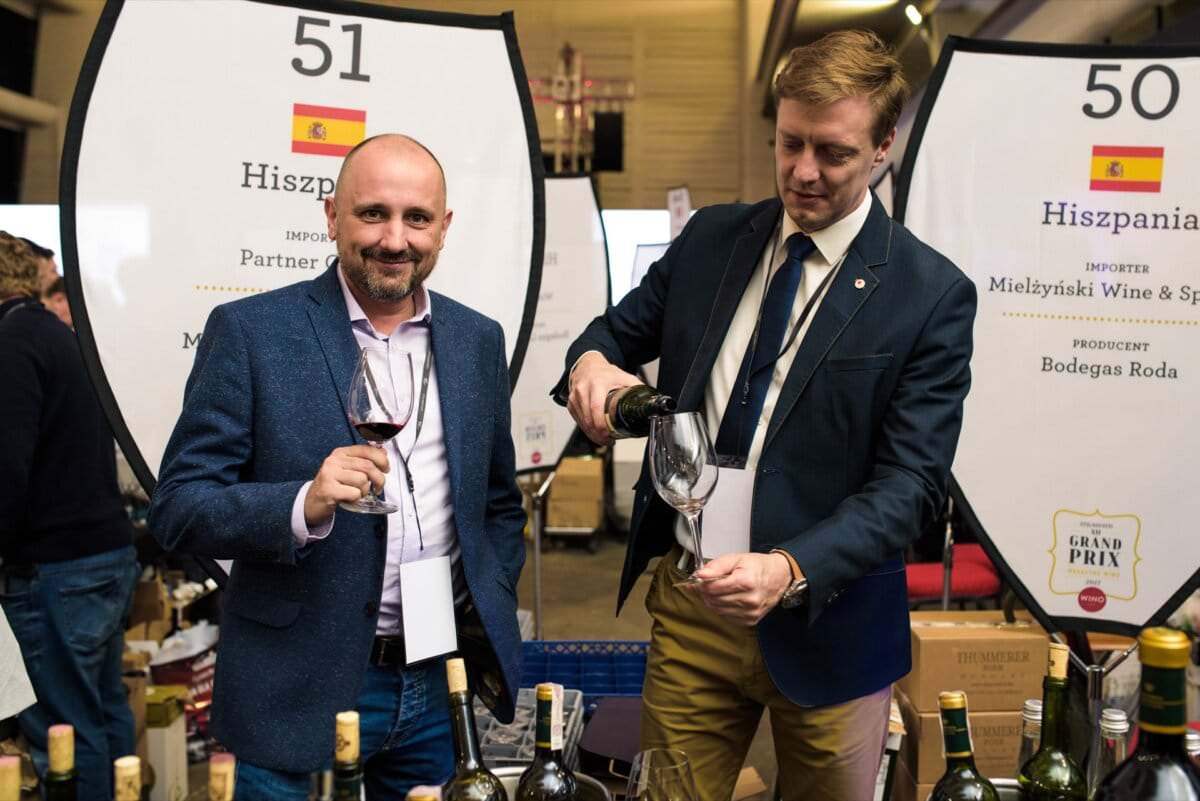 Stoisko z hiszpańskim winem gdzie mężczyżni nalewają wina do kieliszków