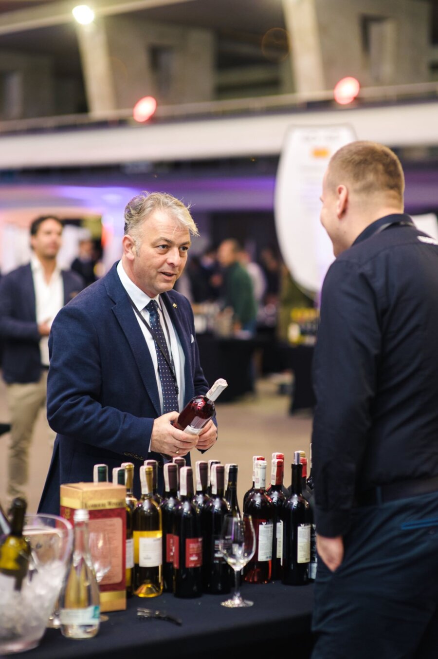 Elegant man holds a bottle of wine while talking about wine