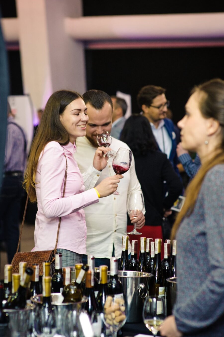 Woman smiles while tasting wine from a glass at wine magazine's grand prix fair