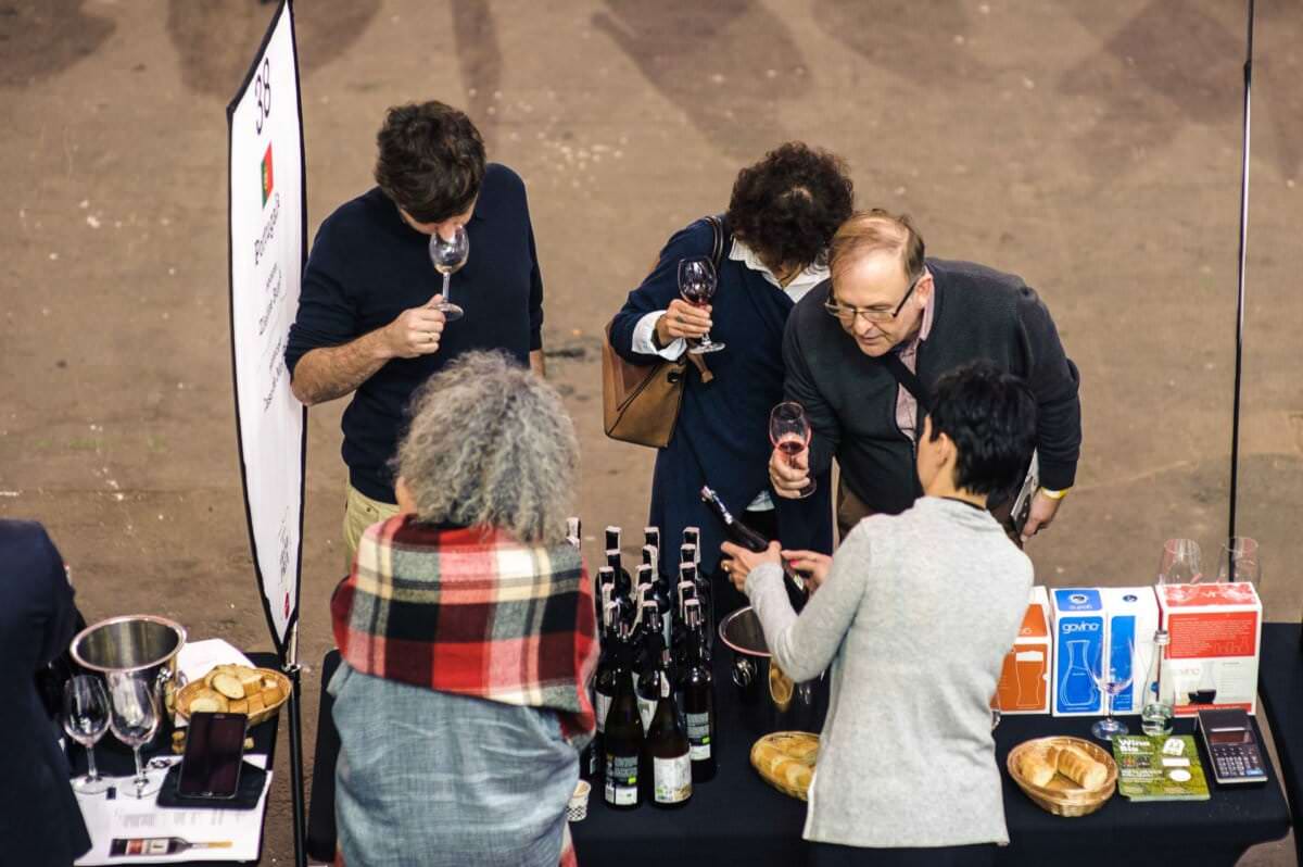Ludzie na stoisko z winami oglądają butelkę i degustują wino
