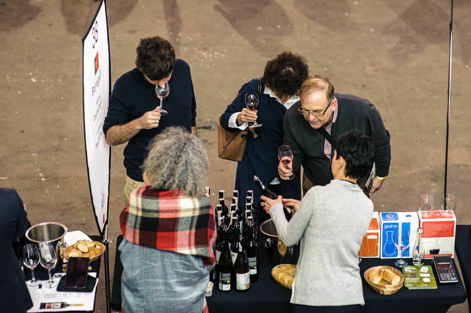 People at the wine stand watch the bottle and taste the wine