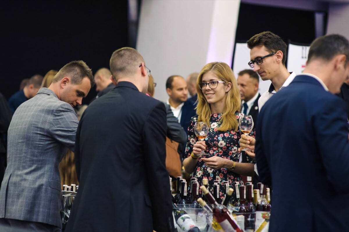 Dziewczyna w okularach trzyma kieliszek z winem na targach