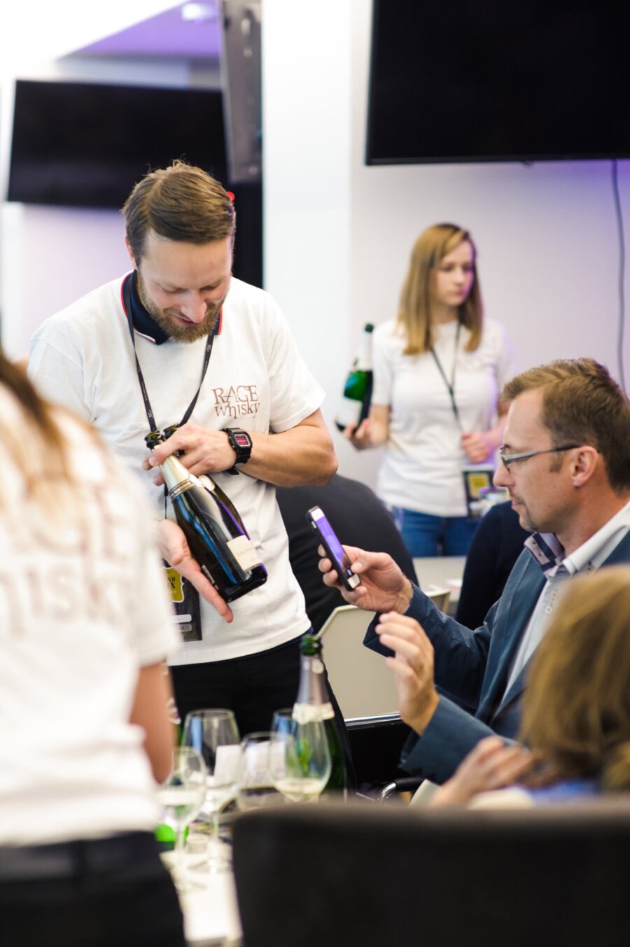 Man in white halter holds bottle of wine for photo