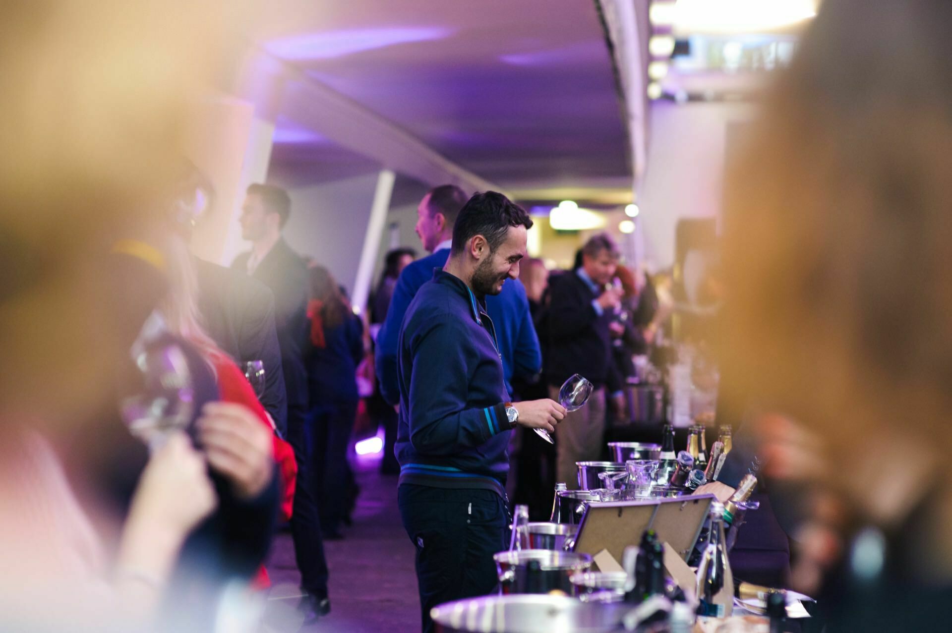 A man with a glass of wine in his hand smiles at a fair