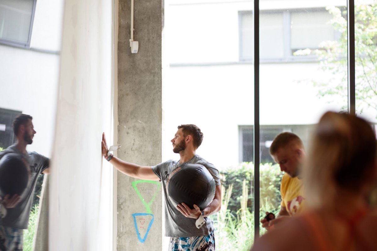 Man with medicine ball touches concrete wall