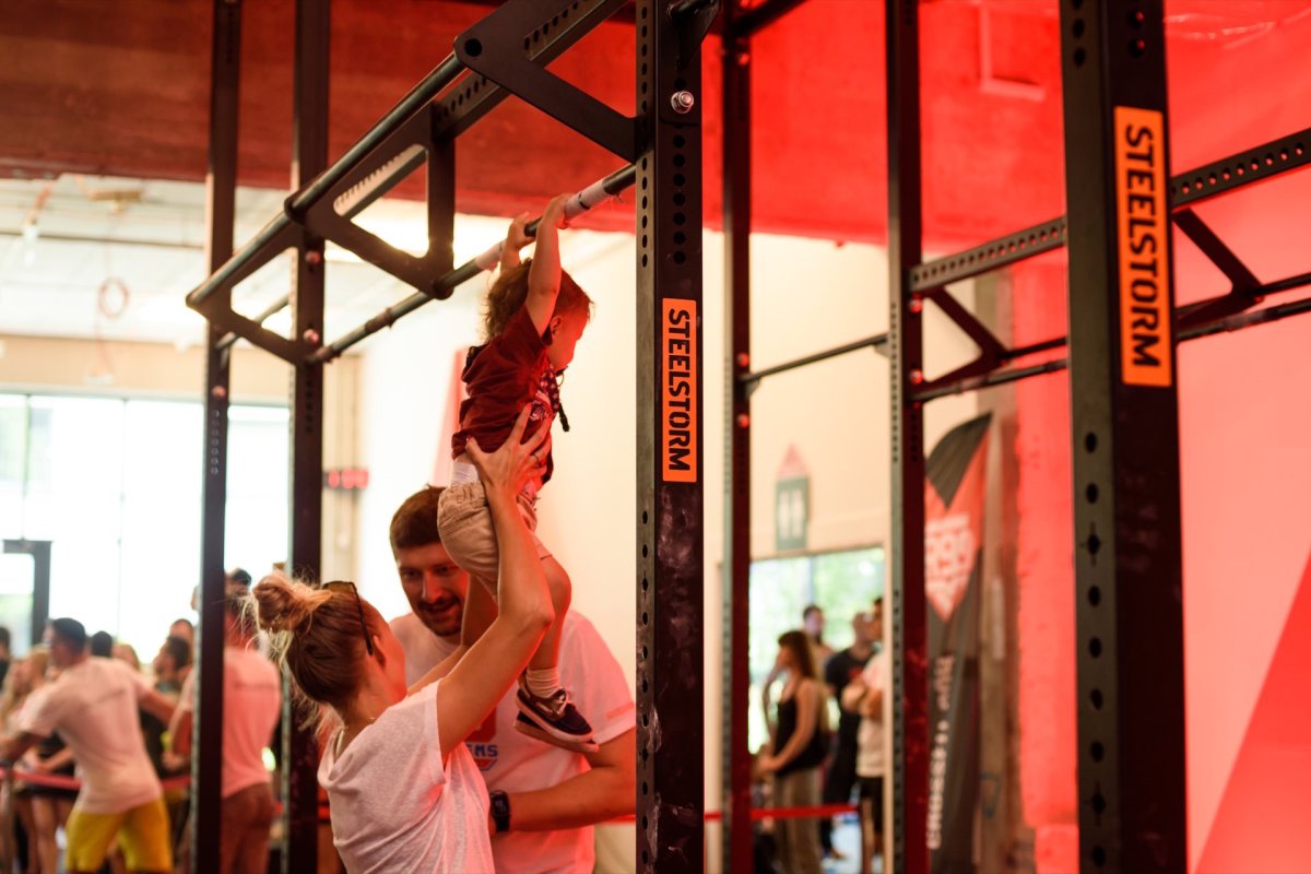 Parents give child a pull-up on a bar