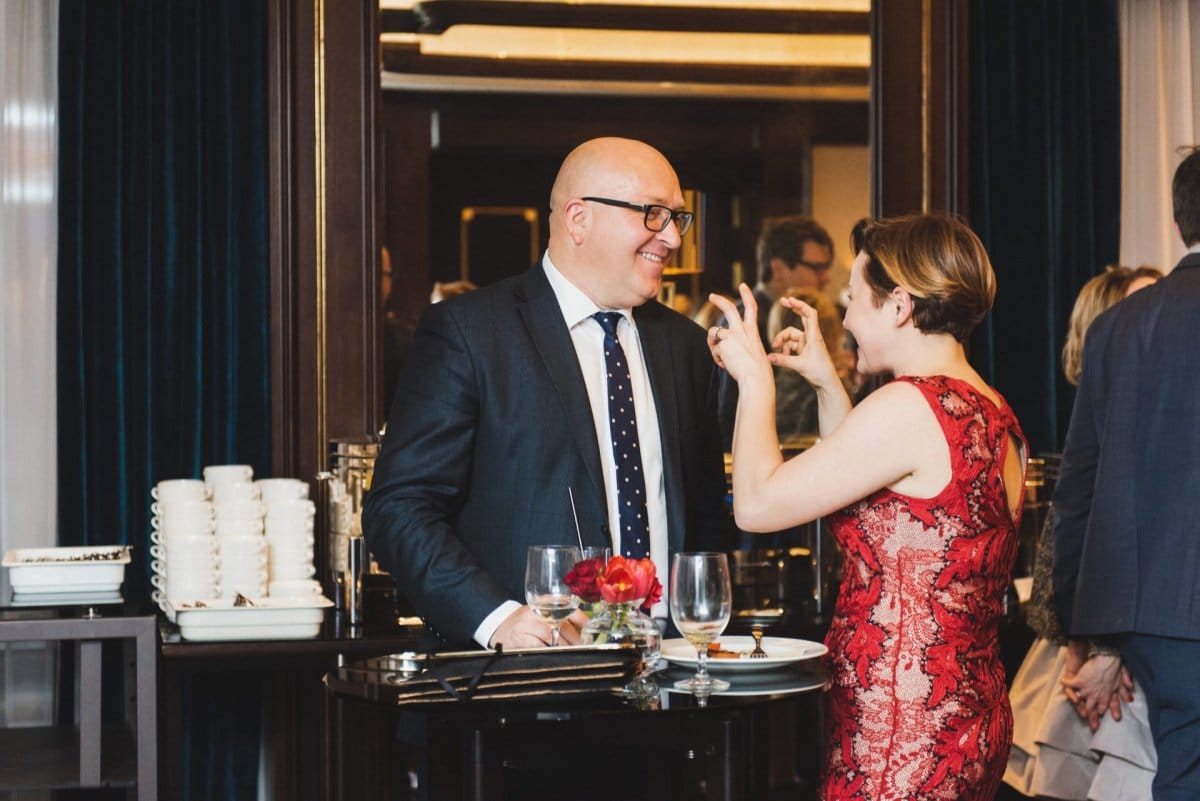 Woman in red dress shows claws to bald man in smart suit