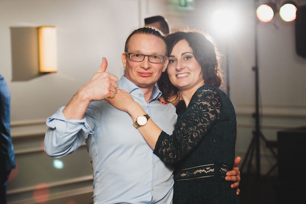 Man with glasses lifts thumb up while standing with woman on dance floor