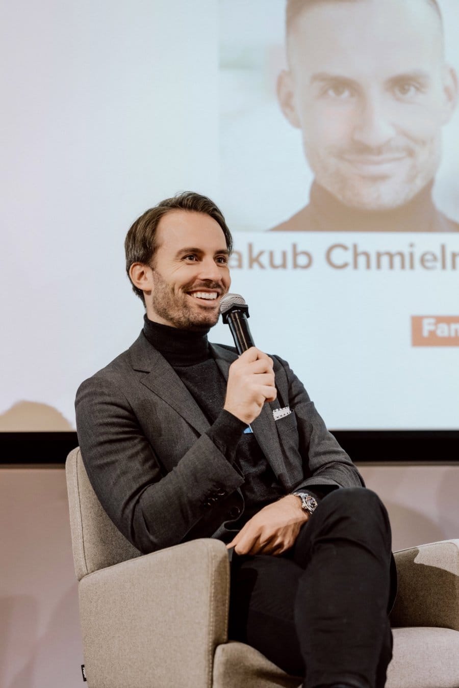 Jakub Chmielniak smiles while holding the microphone at Aula Polska