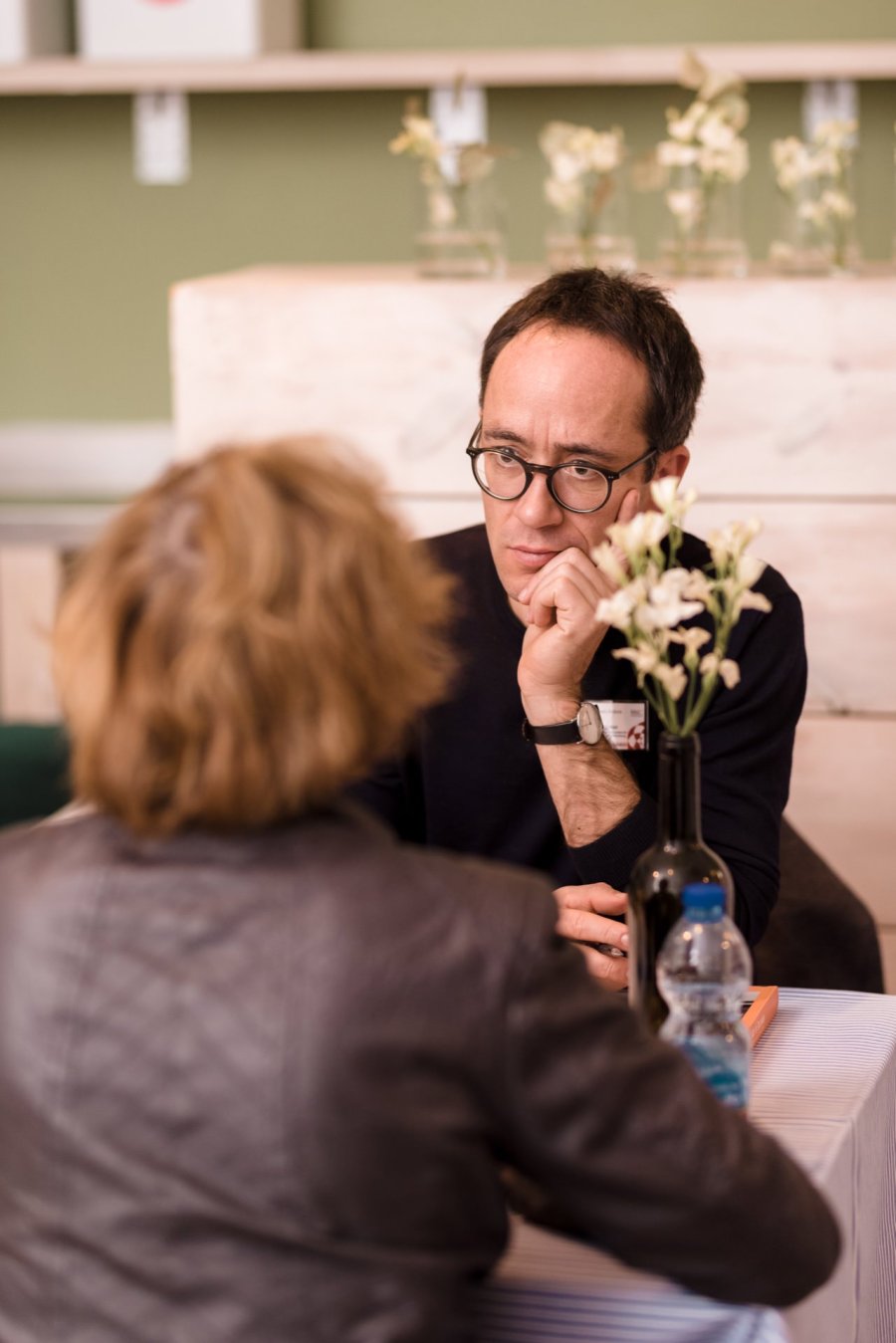 Man with glasses listens to woman at table