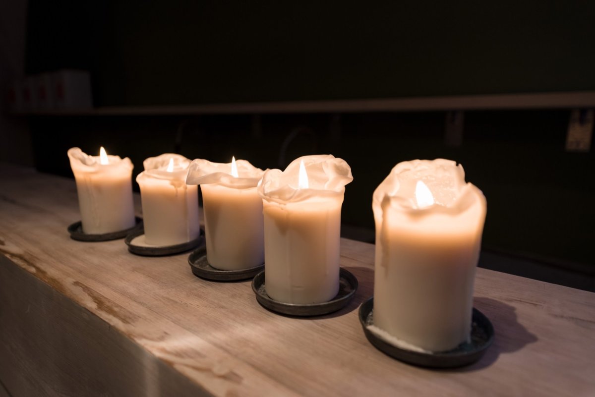 The soft glow of five lit white candles, lined up in a row on a wooden surface, illuminates the dark space. Various amounts of melted wax add to the charm. Such moments are perfectly captured by marcin krokowski, an acclaimed event photographer in Warsaw.  