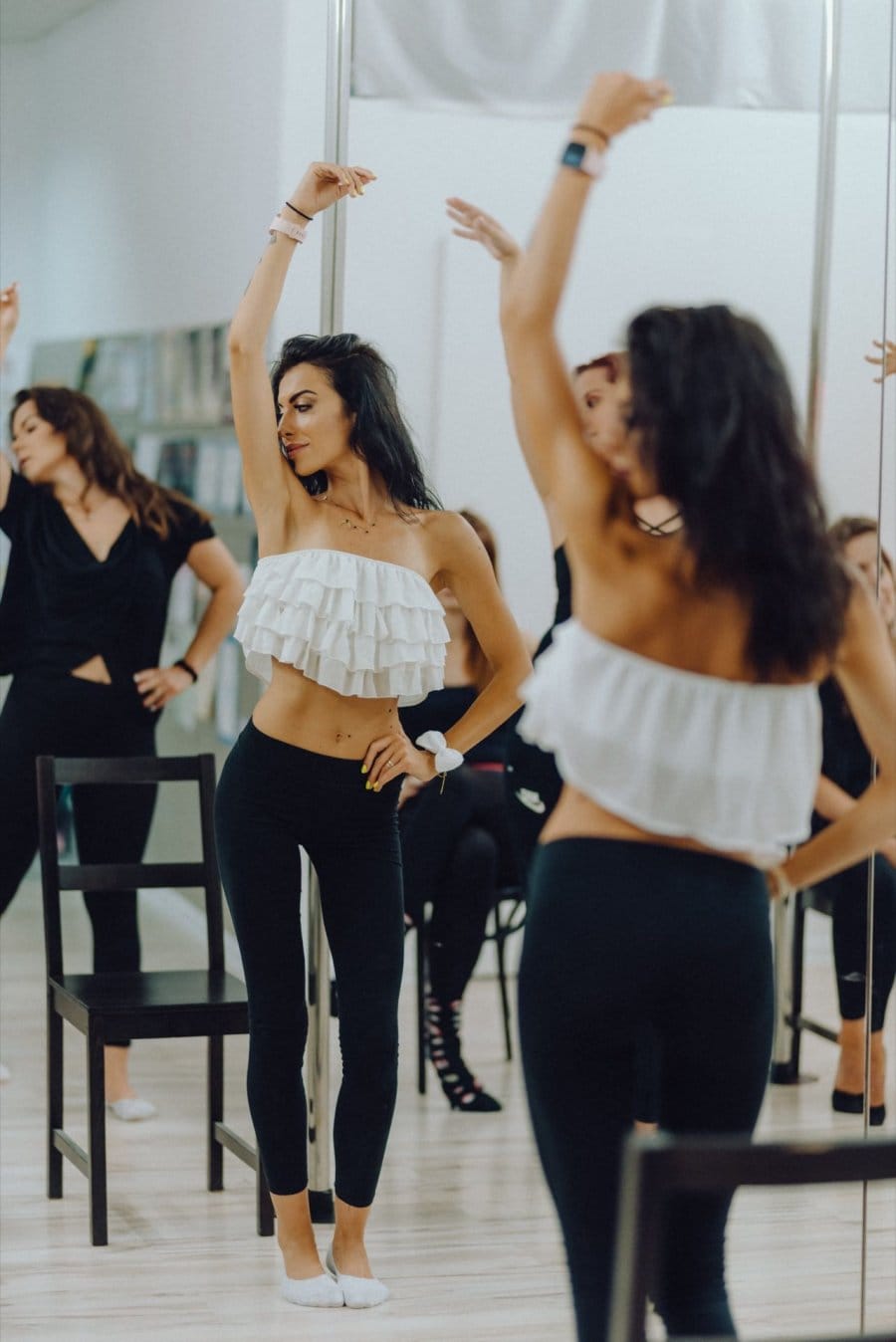 Girls dance in a room in front of a mirror with one hand up