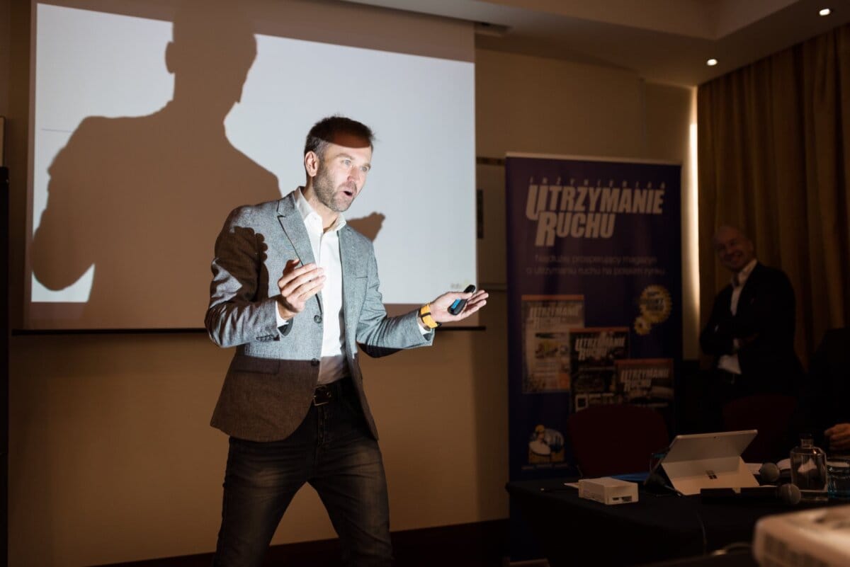 Man speaks gesturing illuminated by harsh projector light