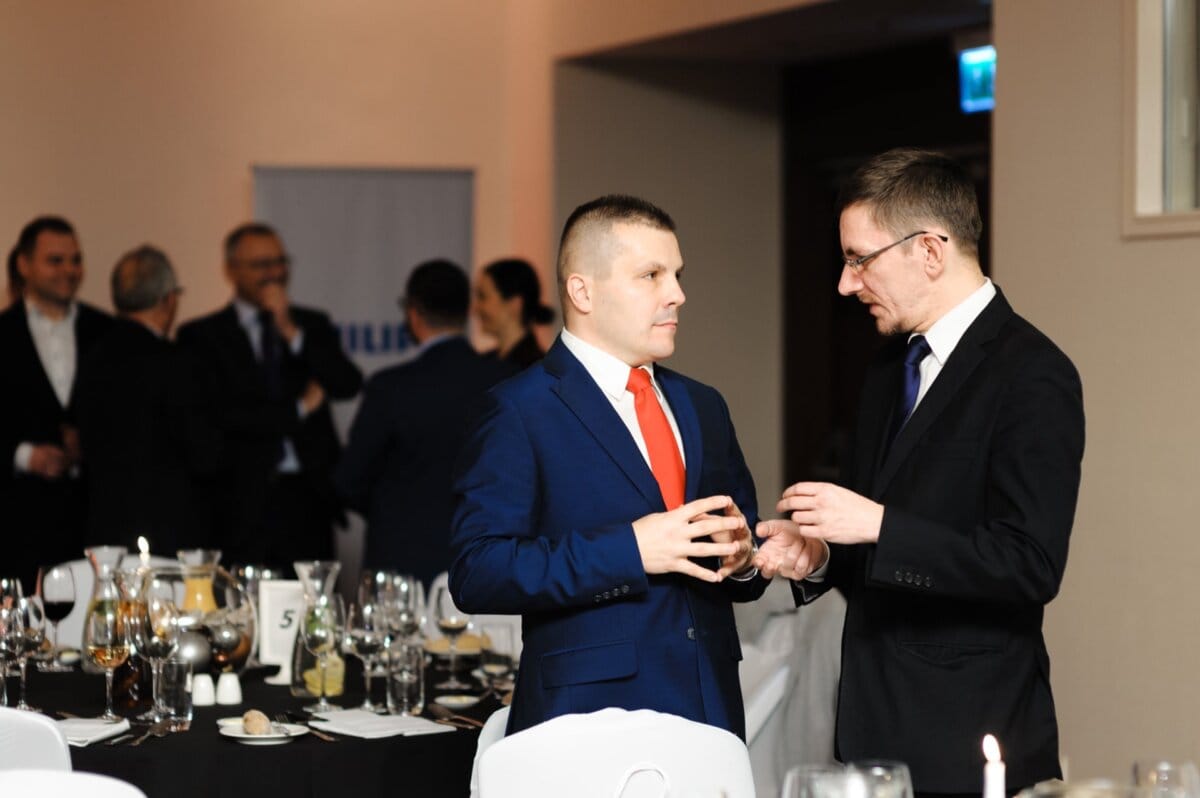 Elegantly dressed men talk standing up at tables