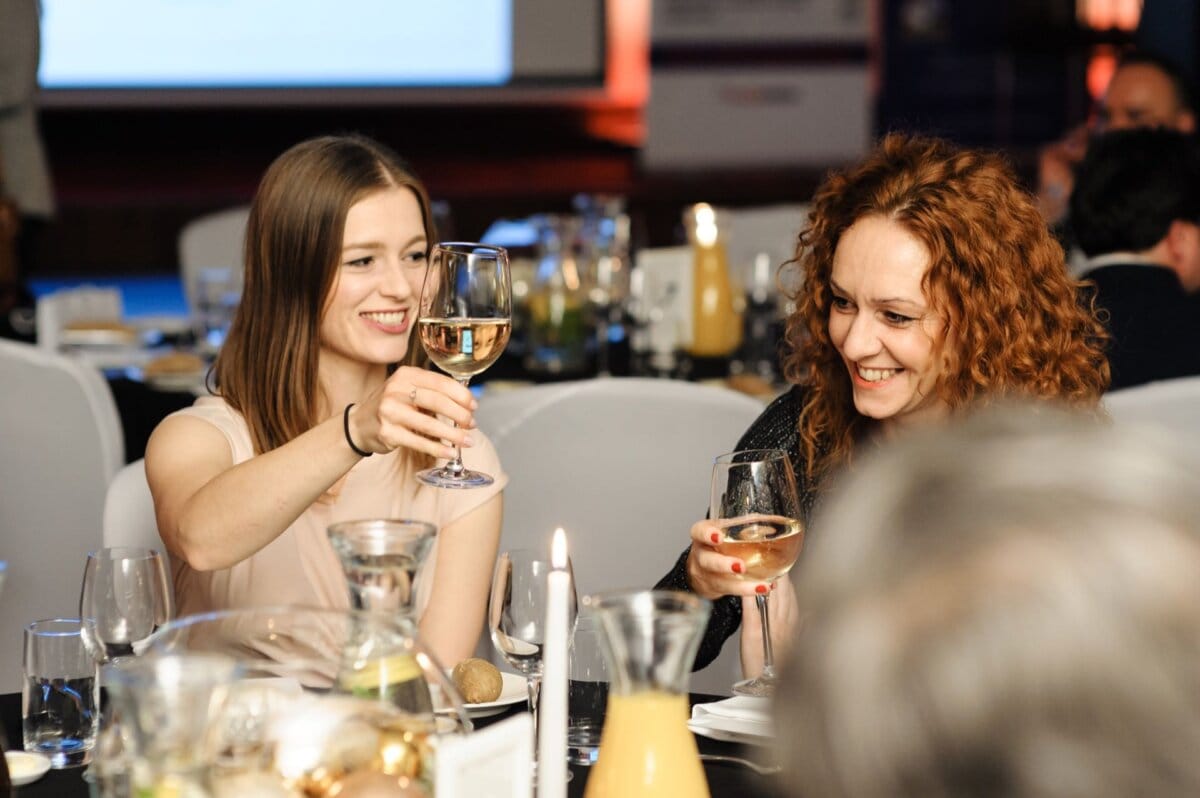 Women at the table bring up their glasses