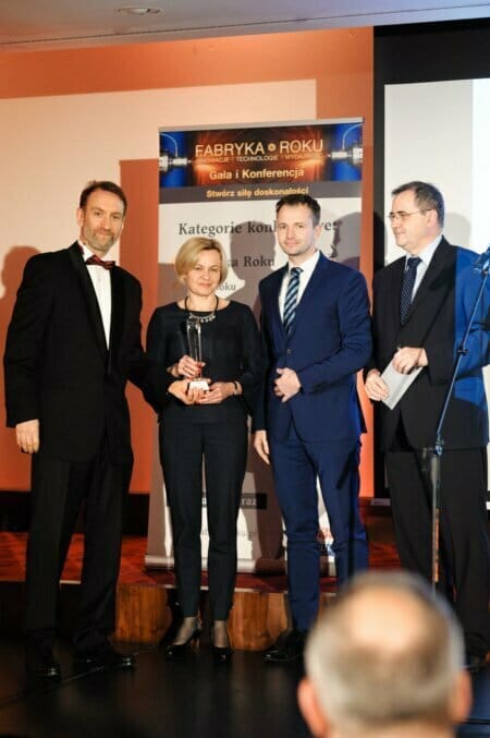 A group of people on stage during the presentation of a glass statuette