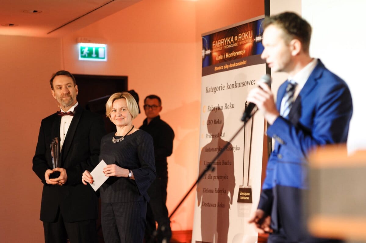 A man speaks into a microphone and two people looking at him