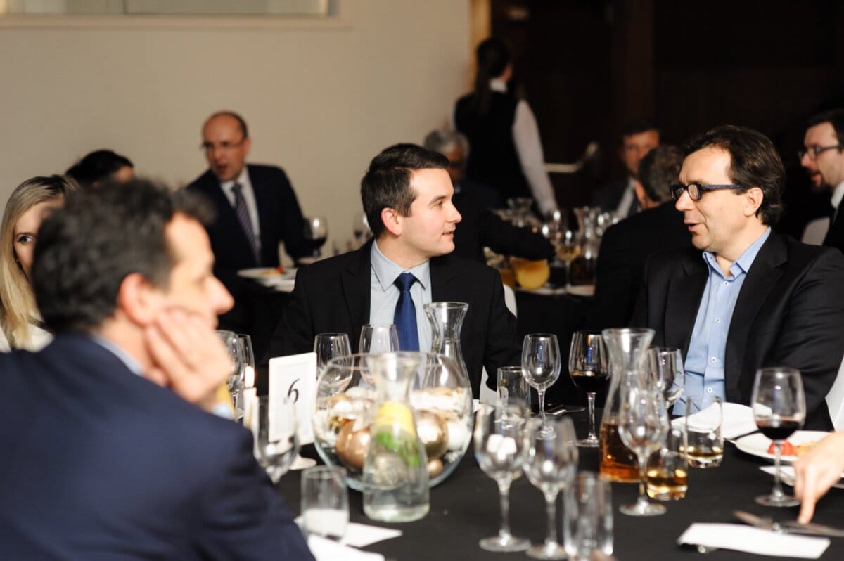 Elegantly dressed men talk at a table