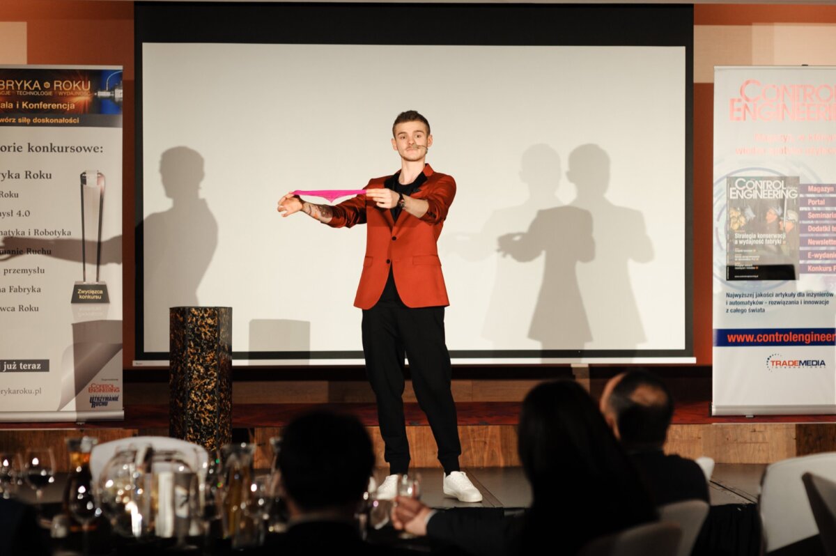 Boy in red jacket holds something pink on stage