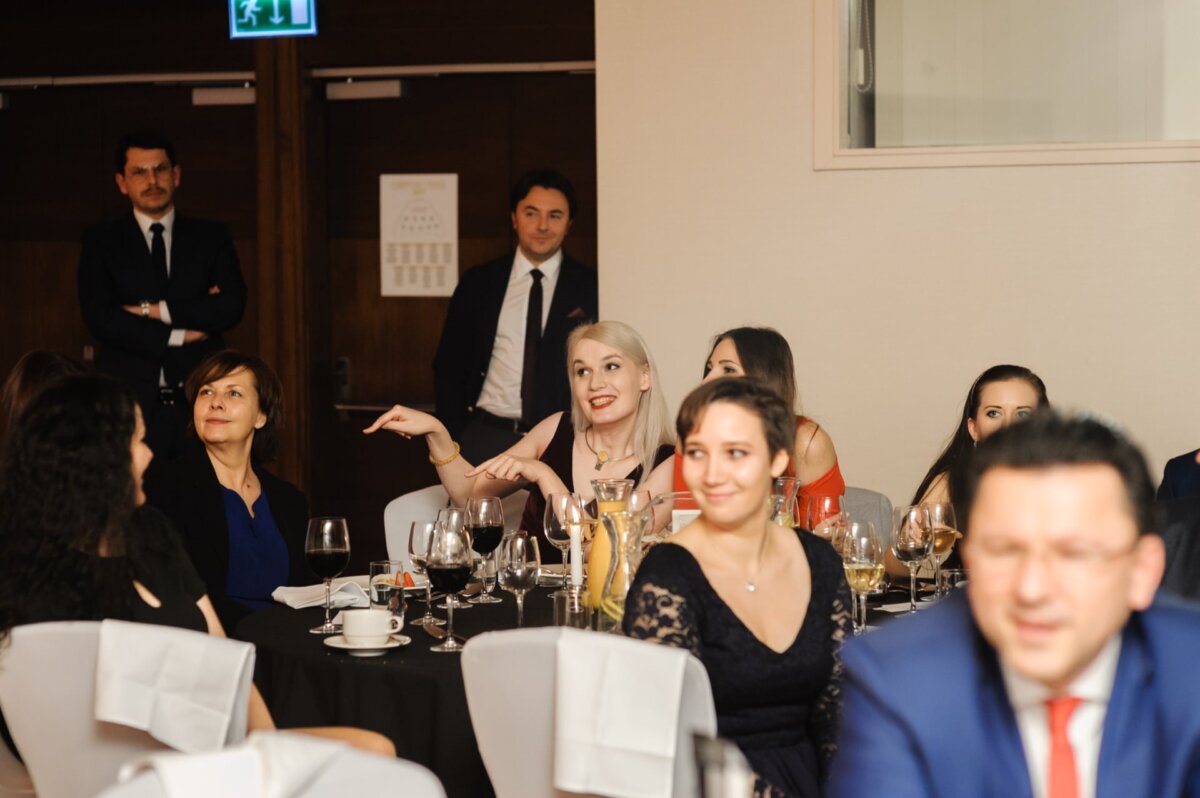 Blonde woman at table points fingers at woman sitting next to her