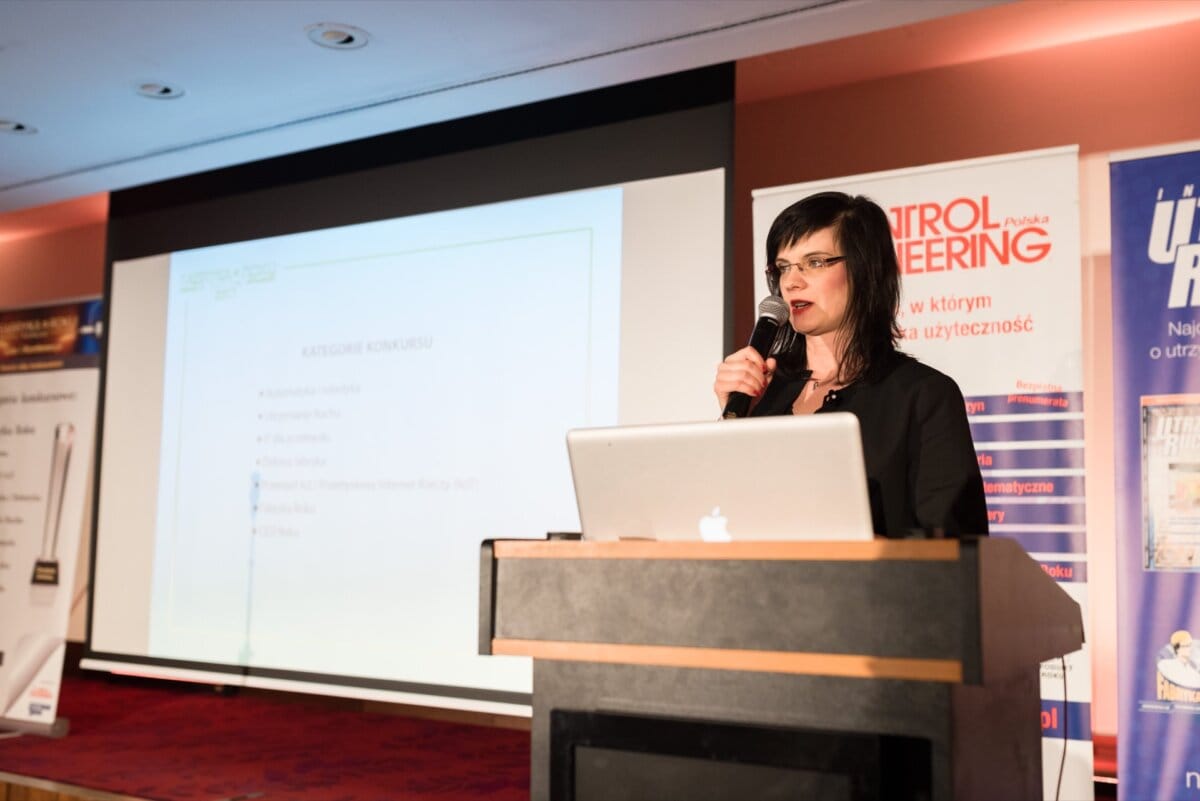 Woman speaking into microphone from behind lectern on which apple computer stands