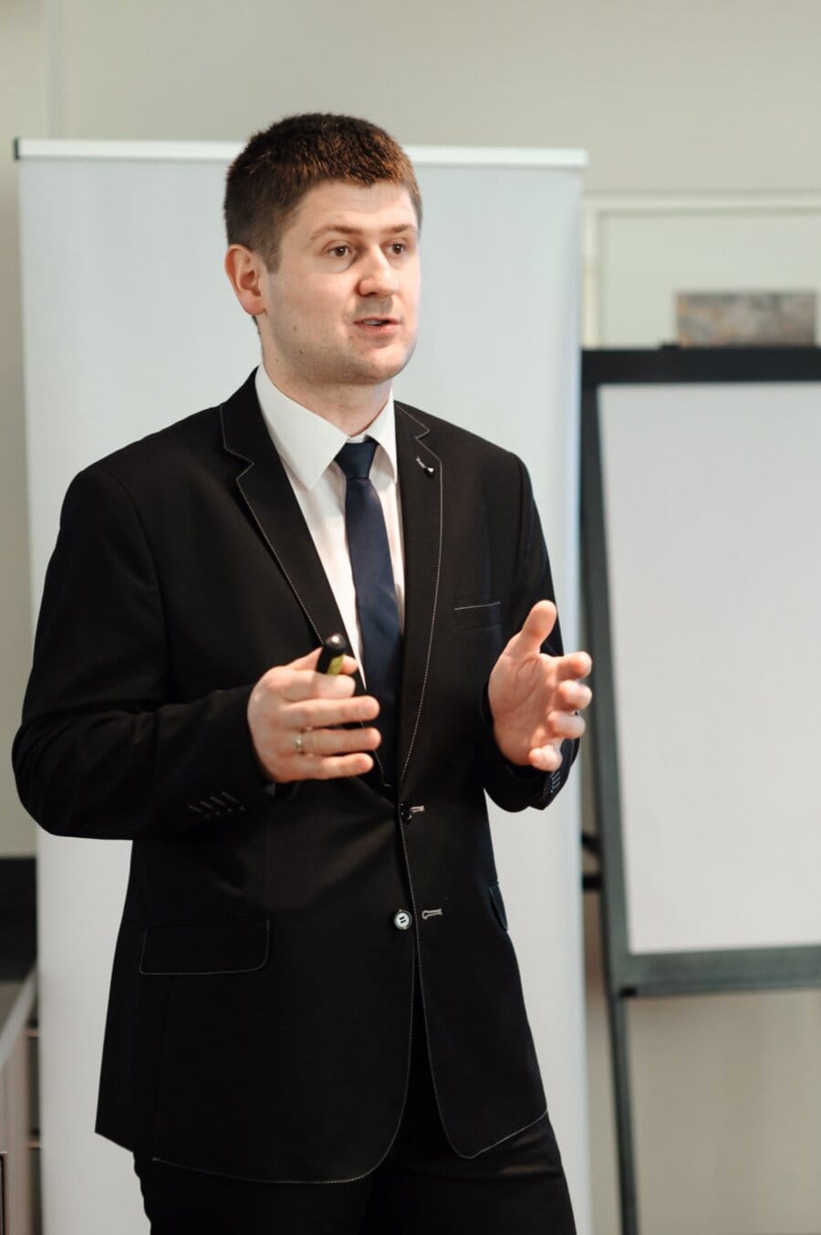 A man in a black suit gestures with his hands