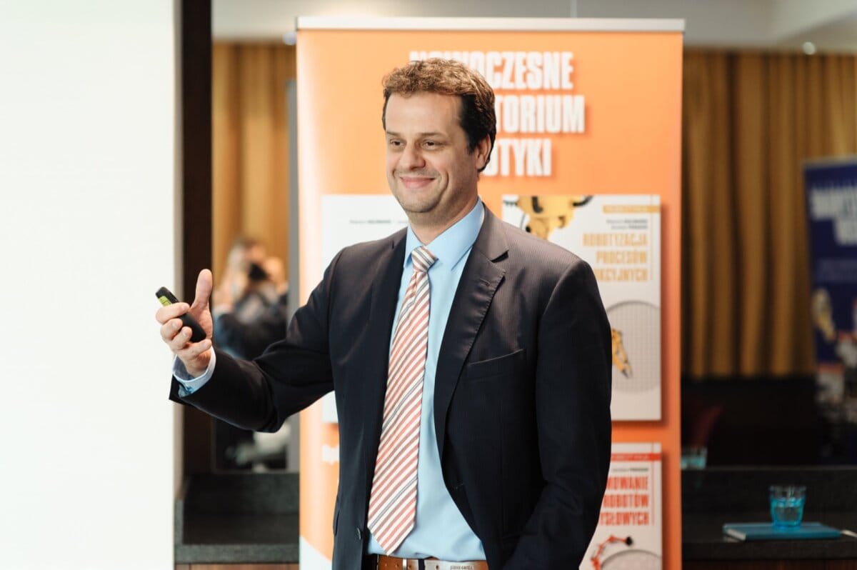 Smiling man on orange background holds remote control to change slides in hand