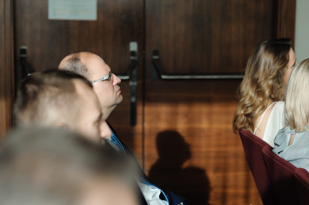 Man with glasses illuminated by harsh light from window during conference