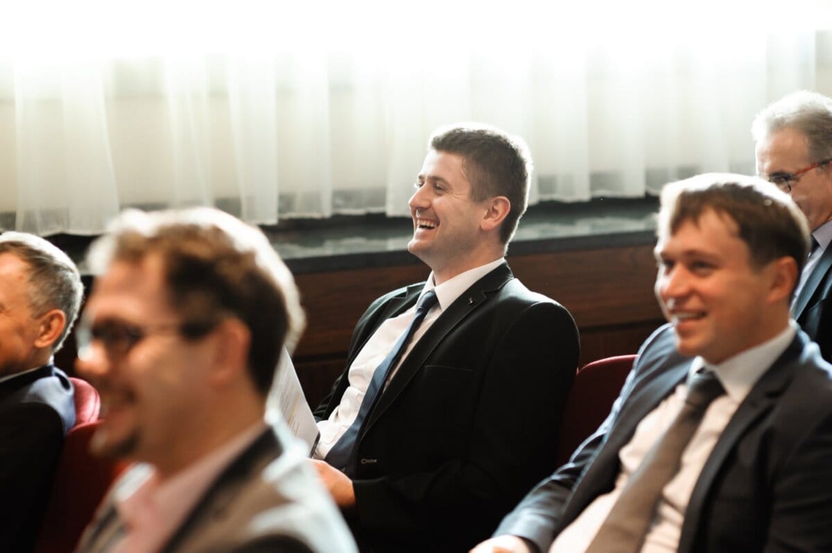 Amused audience sitting on chairs dressed in suits