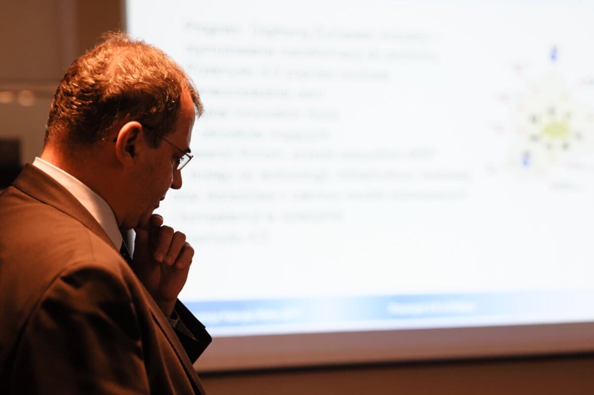 A man holding his hand on his chin in the background of the presentation