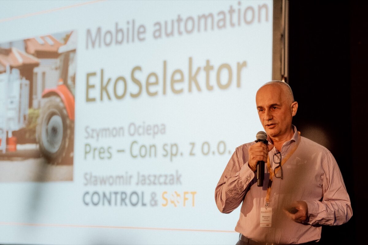 A man stands with a microphone and gives a presentation. On the slide behind him are texts about the companies "Mobile Automation" and "EkoSelektor" along with the names "Szymon Ociepa" and "Slawomir Jaszczak" and the companies "Pres-Con sp. z o.o." and "CONTROL AND MONEY." This moment was captured perfectly for the photo report of the    