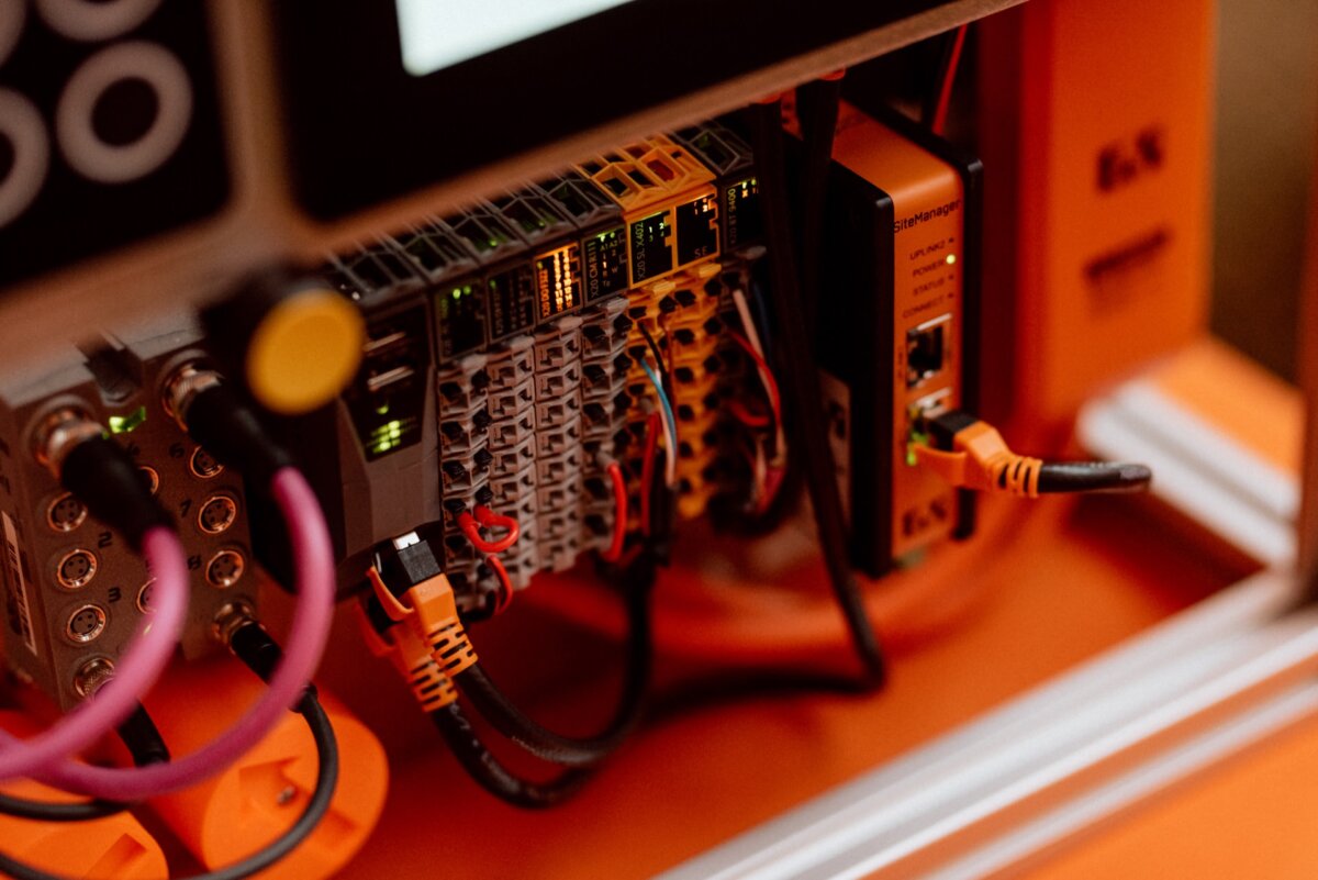 Close-up of a computer server or control panel with various electronic components, cables and indicators. Features Ethernet ports, fused connectors and glowing indicator lights to highlight complex wiring and technical setup - perfect for event photography. 