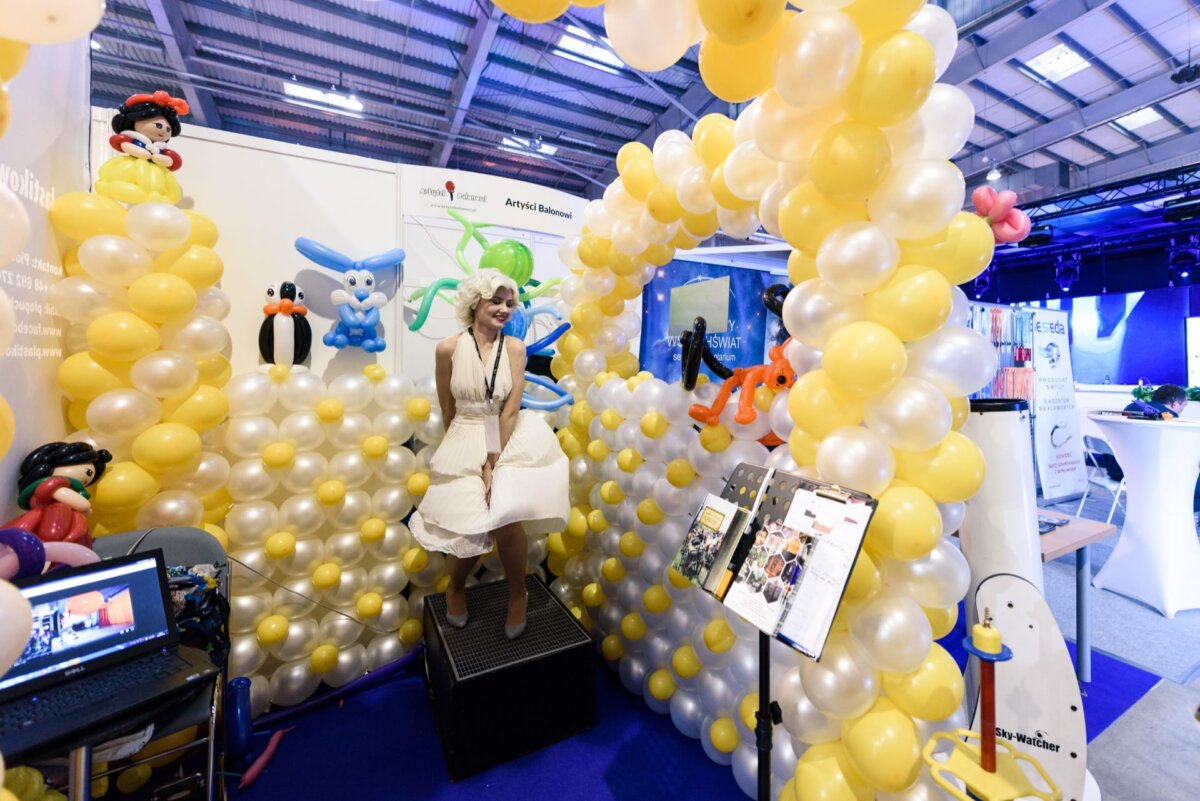 Woman dressed as Marilyn Monroe standing on an inflatable between white and yellow balloons