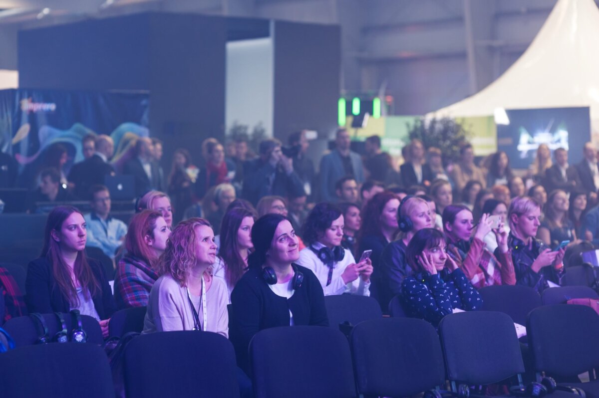 Audience sitting on black chairs in purple light